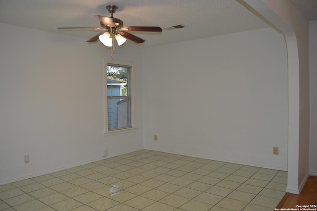unfurnished room featuring a textured ceiling, visible vents, a ceiling fan, and baseboards