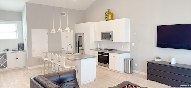 kitchen featuring stainless steel appliances, a sink, visible vents, white cabinetry, and a kitchen breakfast bar