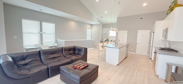 living room with baseboards, visible vents, light wood-style floors, high vaulted ceiling, and recessed lighting