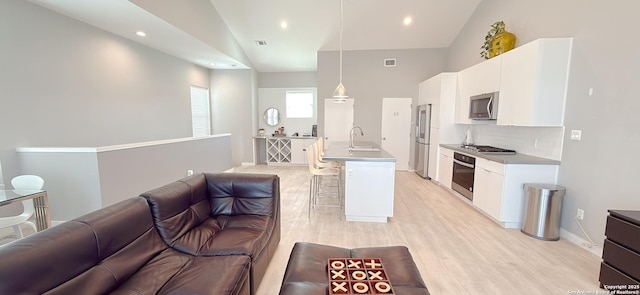 kitchen featuring lofted ceiling, a breakfast bar area, a sink, open floor plan, and appliances with stainless steel finishes