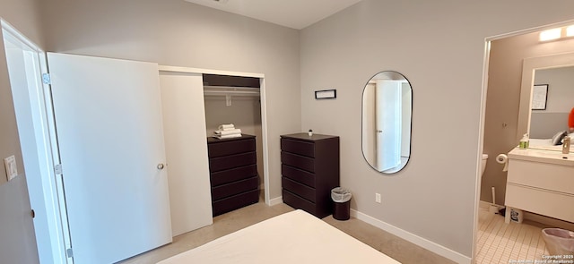 bedroom with a closet, a sink, and baseboards