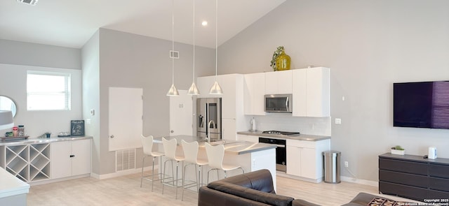 kitchen featuring a center island with sink, visible vents, a breakfast bar area, stainless steel appliances, and backsplash