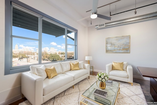 living room featuring a city view, ceiling fan, baseboards, and wood finished floors