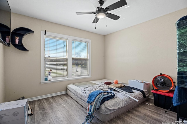 bedroom with a ceiling fan, baseboards, and wood finished floors