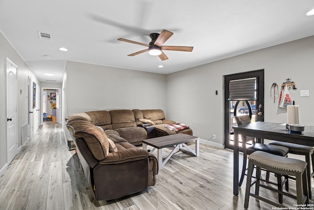 living room with light wood-style flooring, a ceiling fan, visible vents, and baseboards