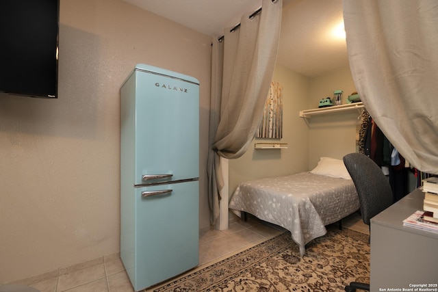 bedroom with freestanding refrigerator and tile patterned flooring