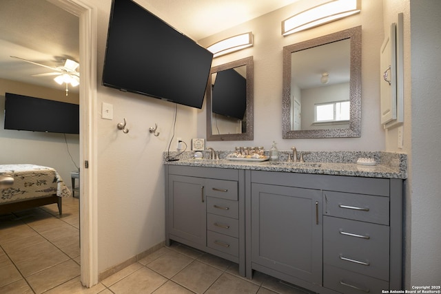 bathroom with double vanity, ensuite bathroom, ceiling fan, a sink, and tile patterned floors