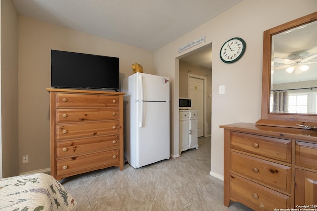 kitchen featuring ceiling fan, freestanding refrigerator, and brown cabinets