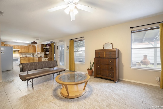 living area with light tile patterned floors, visible vents, baseboards, and ceiling fan