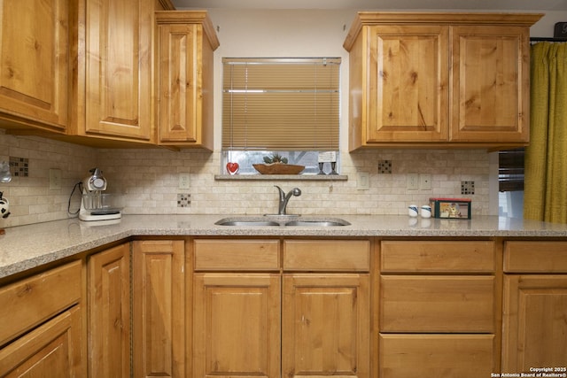 kitchen featuring backsplash, a sink, and light stone countertops