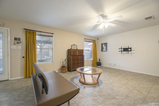 living area with ceiling fan, baseboards, visible vents, and a healthy amount of sunlight