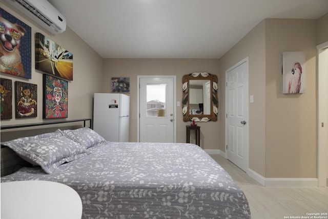 bedroom with a wall unit AC, baseboards, and freestanding refrigerator