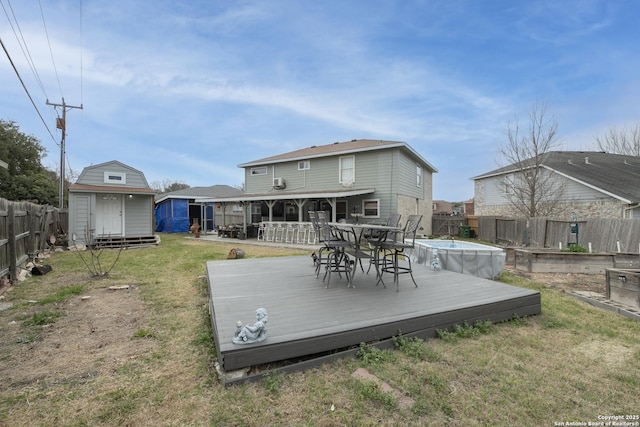 back of property featuring a fenced in pool, an outbuilding, a storage unit, a deck, and a fenced backyard