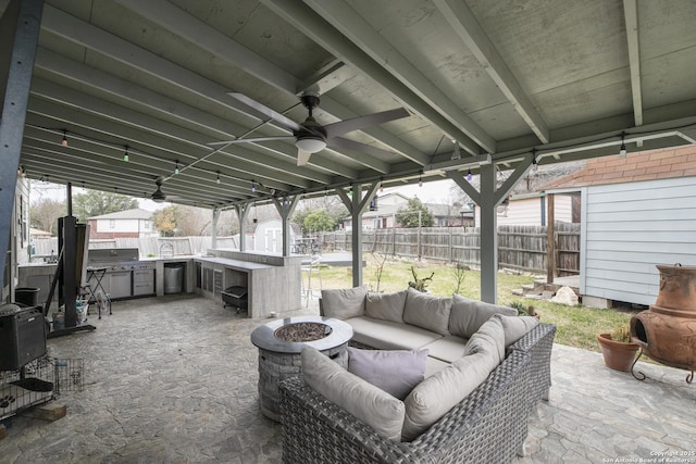 view of patio / terrace with a fenced backyard, area for grilling, a ceiling fan, and an outdoor living space with a fire pit