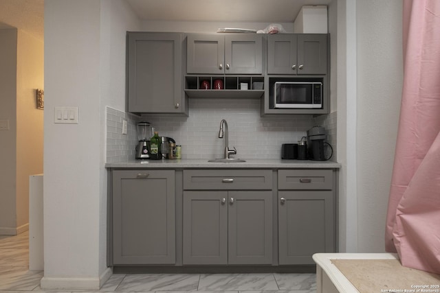 bar with built in microwave, a sink, baseboards, marble finish floor, and decorative backsplash