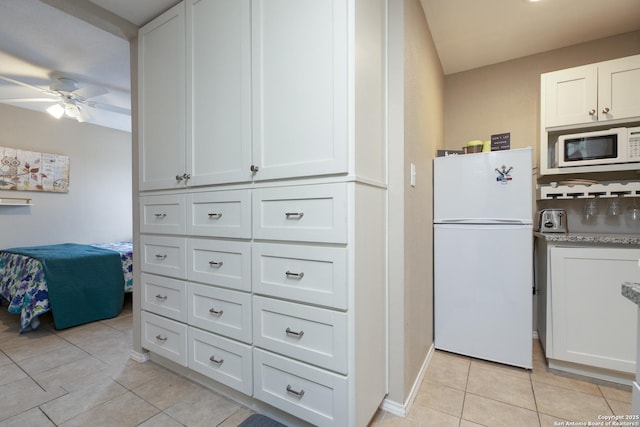 kitchen with white appliances, light tile patterned floors, baseboards, a ceiling fan, and white cabinetry