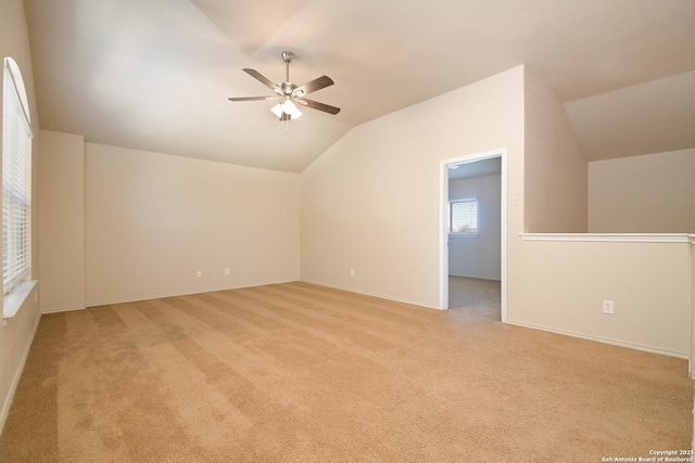 interior space with a ceiling fan, lofted ceiling, light carpet, and baseboards