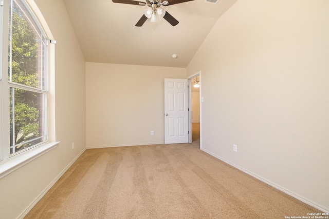 empty room featuring ceiling fan, light colored carpet, visible vents, baseboards, and vaulted ceiling