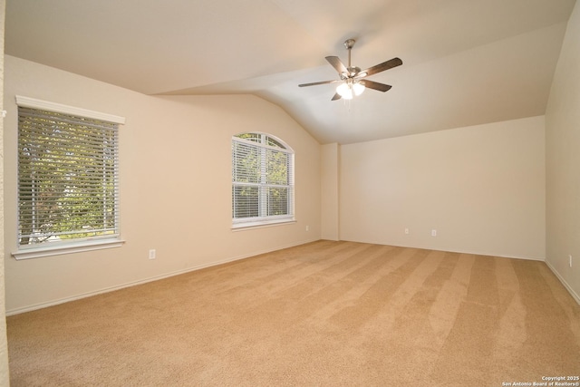 unfurnished room with vaulted ceiling, a ceiling fan, and light colored carpet