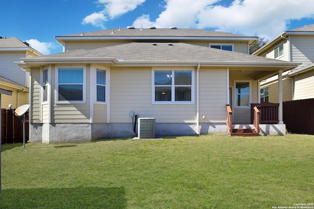 rear view of house featuring central AC, a lawn, and fence