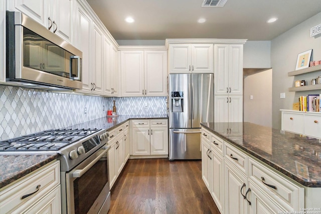 kitchen featuring dark wood-type flooring, white cabinetry, appliances with stainless steel finishes, open shelves, and dark stone countertops