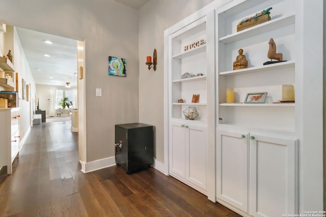 hallway with built in shelves, dark wood-style flooring, recessed lighting, and baseboards