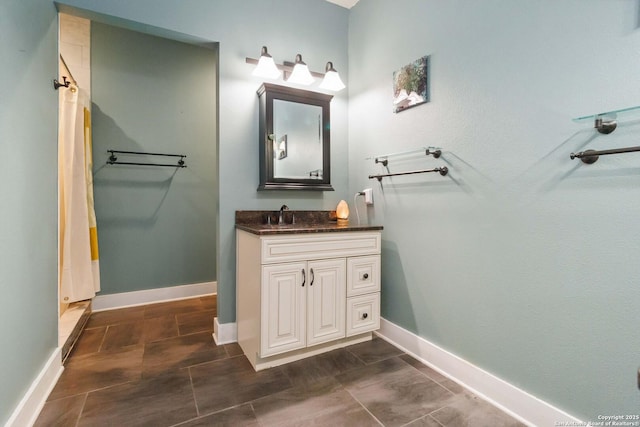 bathroom with curtained shower, vanity, and baseboards