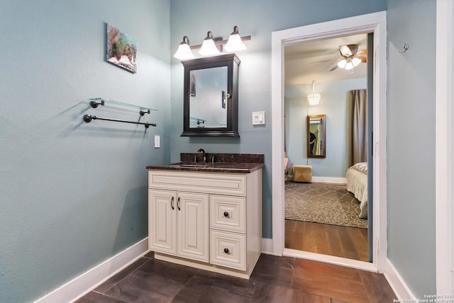 bathroom featuring a ceiling fan, baseboards, vanity, tile patterned floors, and ensuite bath