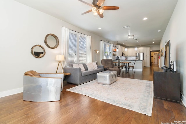 living room featuring ceiling fan, recessed lighting, visible vents, baseboards, and dark wood-style floors