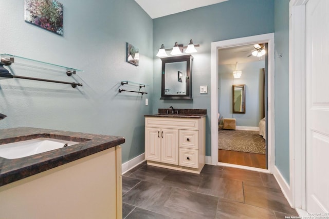 bathroom featuring ensuite bath, vanity, and baseboards