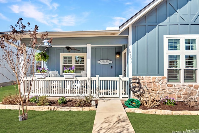 view of front of home with covered porch, ceiling fan, stone siding, and board and batten siding