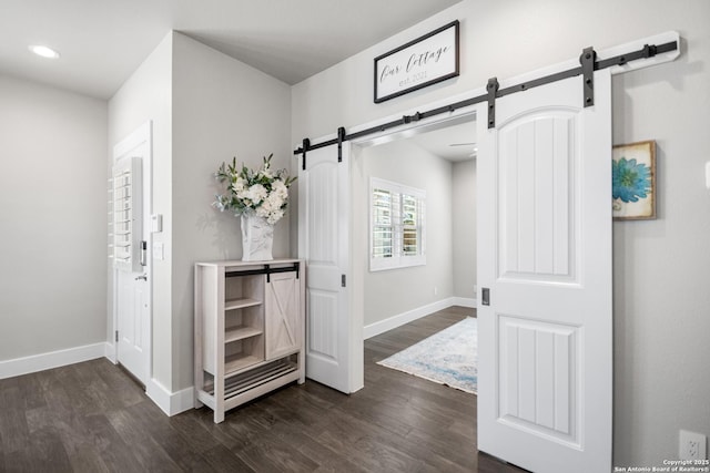 interior space featuring a barn door, recessed lighting, wood finished floors, and baseboards