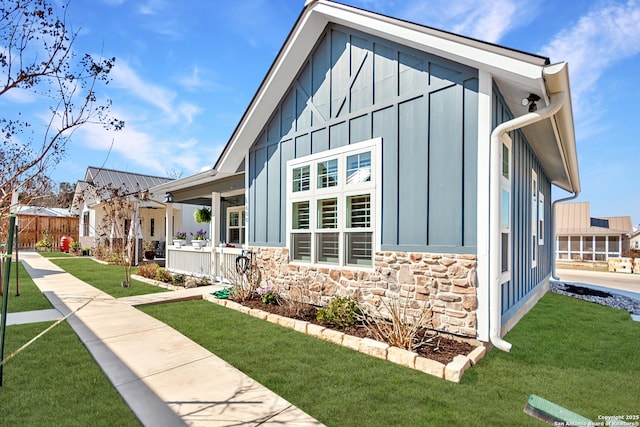 view of property exterior featuring stone siding, a yard, and board and batten siding