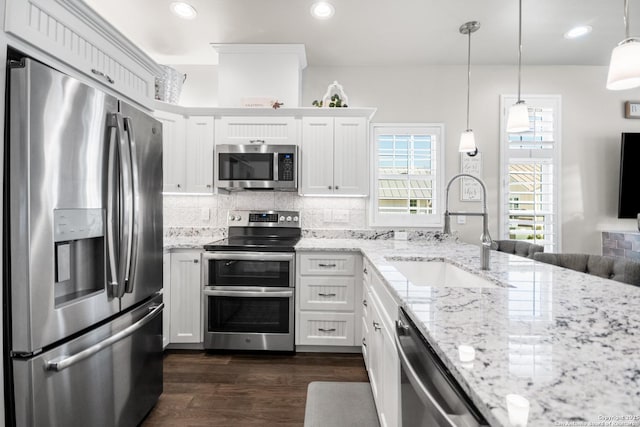 kitchen with white cabinets, dark wood finished floors, appliances with stainless steel finishes, a sink, and backsplash