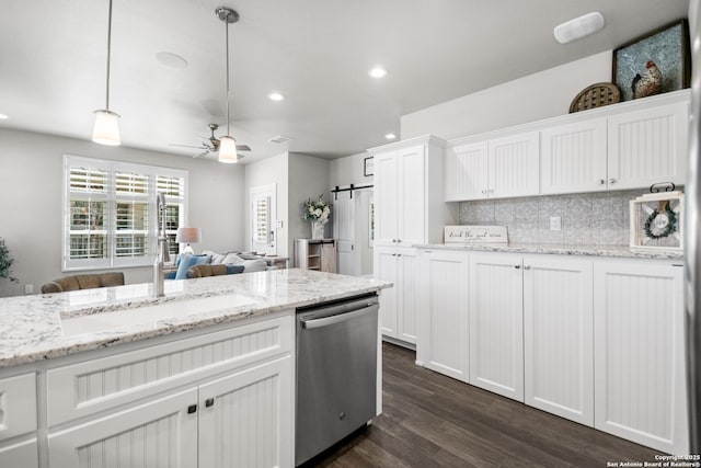 kitchen with tasteful backsplash, a barn door, white cabinets, dishwasher, and dark wood-type flooring