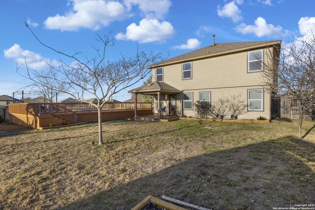 back of property with a yard, fence, and a deck