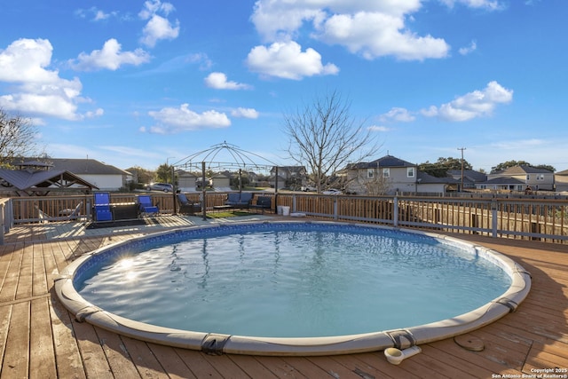 view of swimming pool with a deck, a fenced backyard, and a residential view