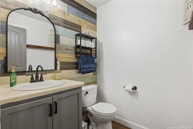 bathroom with toilet, baseboards, and vanity