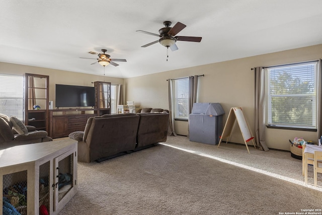 living area featuring carpet, plenty of natural light, and ceiling fan