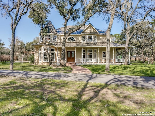 victorian house featuring covered porch, french doors, and a front yard