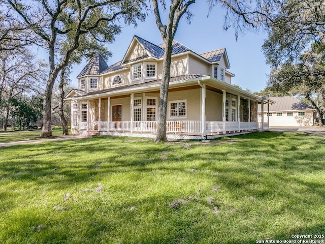 victorian-style house featuring covered porch, metal roof, a standing seam roof, and a front yard