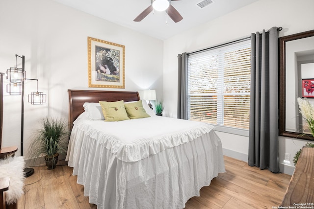 bedroom featuring light wood finished floors, baseboards, multiple windows, and visible vents