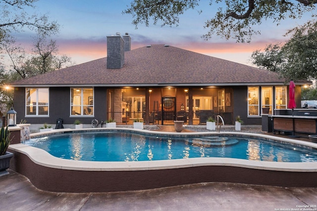 pool at dusk with a patio area and an outdoor pool