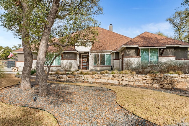 view of front of house featuring a shingled roof and a chimney