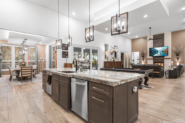 kitchen featuring a fireplace, a sink, dark brown cabinetry, and light wood-style floors