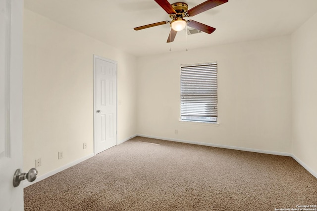 carpeted empty room with baseboards, visible vents, and ceiling fan