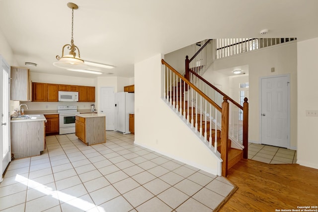 kitchen with a center island, light tile patterned floors, light countertops, a sink, and white appliances