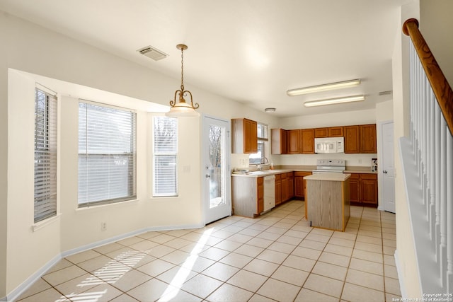 kitchen featuring light tile patterned floors, white appliances, a sink, visible vents, and light countertops