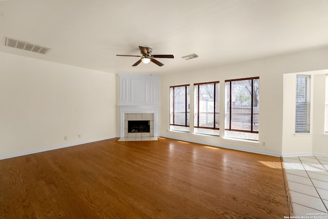 unfurnished living room featuring light wood finished floors, a fireplace, visible vents, and a ceiling fan