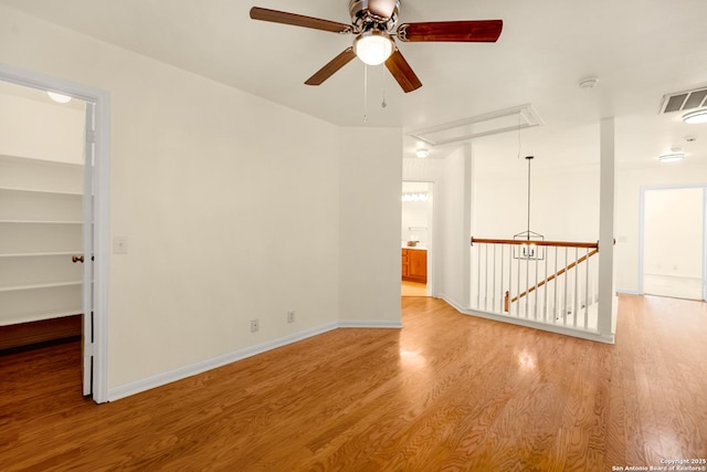 unfurnished room with baseboards, attic access, visible vents, and wood finished floors